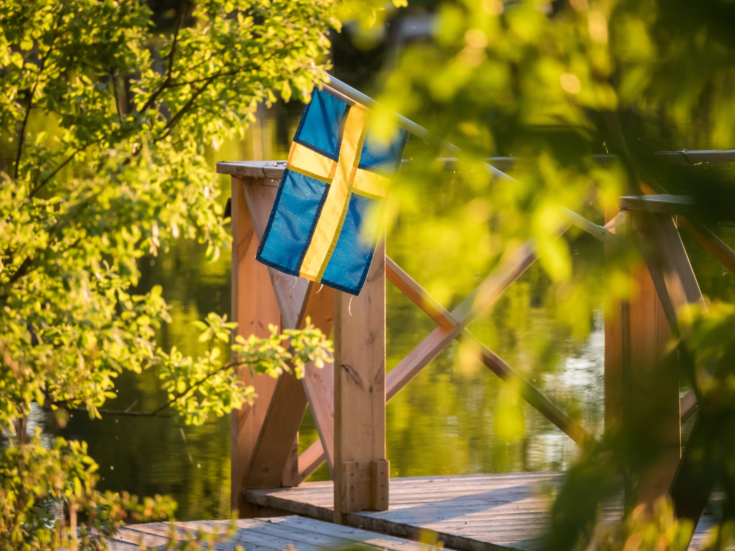 Swedish flag on a floating dock in summer sunset light in Sweden. Swedish flag on a floating dock in summer sunset light in Sweden.